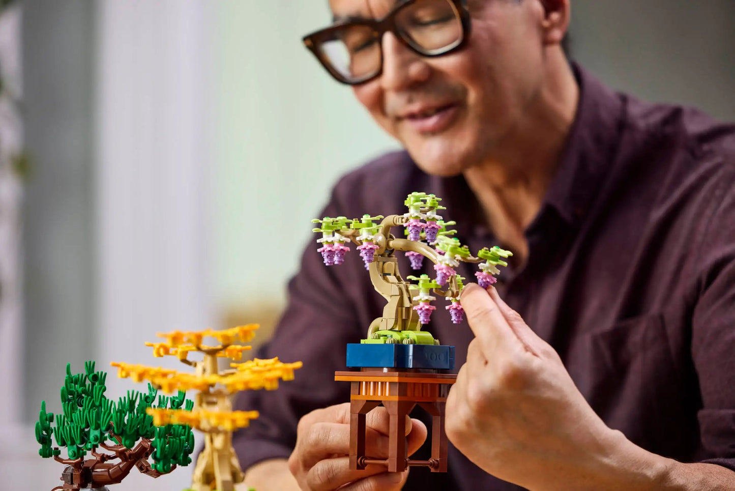 Volwassen man ontspant en bouwt de LEGO Botanicals 10373 Mini bonsaiboompjes